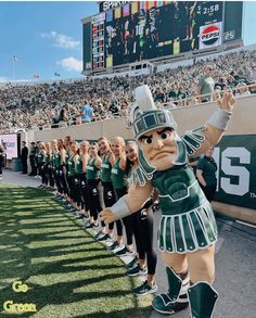 the michigan state marching team is dressed in green and white uniforms, standing on the sidelines