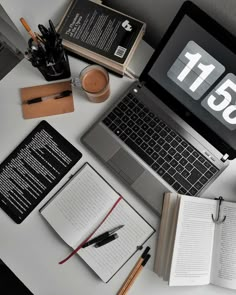 an open laptop computer sitting on top of a desk next to books and other items