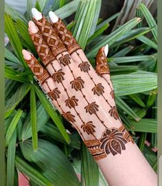 a woman's hand with henna on it and palm leaves in the background