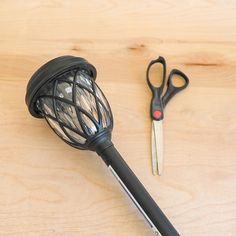 a wire ball and scissors on a wooden surface