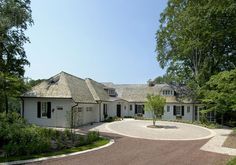 a large white house surrounded by lots of trees and bushes with a driveway leading to it