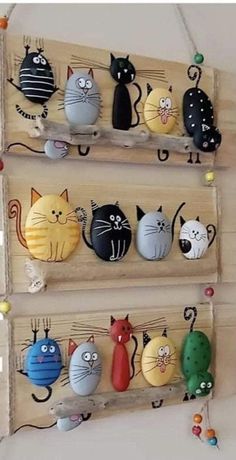 three wooden pegs with cats on them hanging from the ceiling and one is holding several magnets