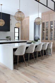 a large kitchen with an island and bar stools next to the countertop area