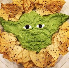 a plate with chips and guacamole in the shape of an alien face