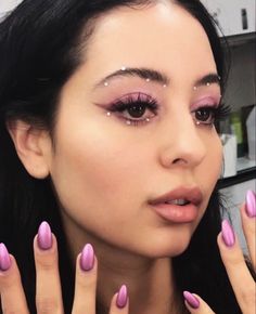 a woman with pink nail polish holding her hands up in front of her face and looking at the camera