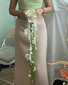 a woman holding a flower bouquet in her hand and wearing a green top with white flowers on it