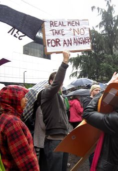 a group of people holding up signs and umbrellas