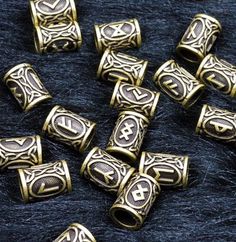 brass plated beads with designs on them are laying on a black surface next to other beads