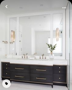 a bathroom with two sinks, mirrors and lights on the wall above it is white tile flooring