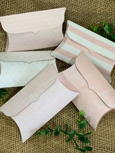 four pieces of pink paper sitting on top of a burlock covered table cloth