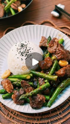 a white plate topped with meat and asparagus next to a bowl of rice