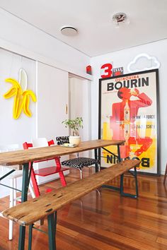 a wooden table sitting on top of a hard wood floor next to a wall mounted poster