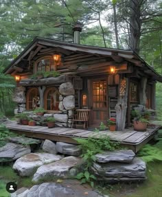 a small log cabin in the woods with rocks and plants on the front porch is lit by lanterns