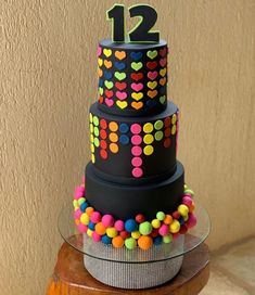 a multi - tiered cake decorated with colorful candies and the number twelve on top