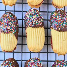 several cupcakes with chocolate frosting and sprinkles on a cooling rack