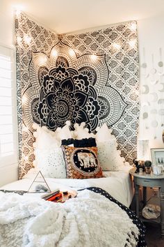 a bed with white sheets and black and white wallpaper on the headboard is decorated with lights