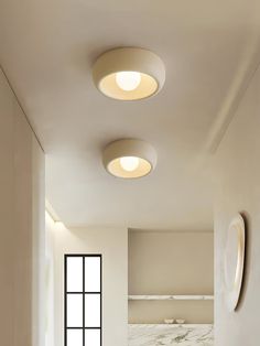 three circular lights are hanging from the ceiling in this modern bathroom with marble countertops