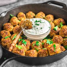 a skillet filled with meatballs and dipping sauce on the side, ready to be eaten