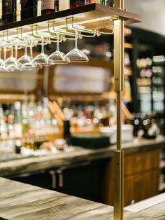 a bar with wine glasses hanging from it's ceiling and bottles on the shelves