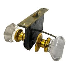 two glass door knobs are attached to a brass plated latch on a white background