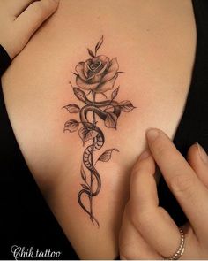 a woman's shoulder with a rose and snake tattoo on the left side of her arm