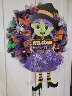 a purple wreath with a witch on it and the words welcome my prettis