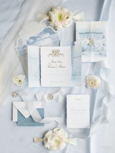 the wedding stationery is laid out with flowers and ribbons on it's side