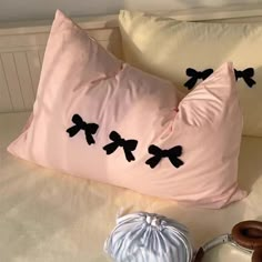 a pillow with black bows on it sitting on a bed next to two donuts