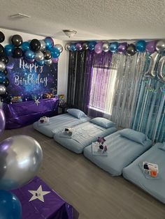 a room filled with lots of blue and purple balloons on top of bedding,