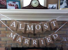 a sign that says almost married hanging from a fireplace mantel with a clock in the background