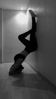 black and white photograph of a woman leaning against the wall with her legs up in the air