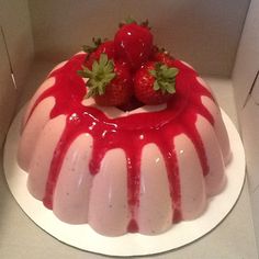 a white cake with strawberries on top in a box