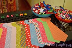 a table topped with lots of different colored papers and bowls filled with confetti