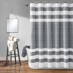 a gray and white striped shower curtain next to a stool with a mirror on the wall