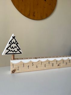 a wooden ruler sitting on top of a white table next to a wall mounted clock