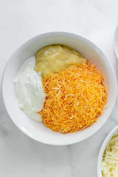 two bowls filled with different types of cheese and sauces on top of a table