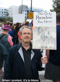 a man holding up a sign that says the only revolver you need when protest, it's in mono