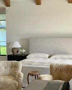 a laptop computer sitting on top of a bed in a bedroom next to two chairs