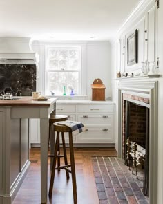 a kitchen with an oven, stove and bar stools in front of the fireplace