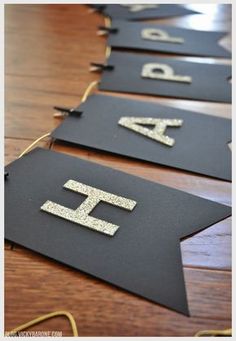 black and gold banner with glitter letters on it sitting on a wooden table in front of a wood floor