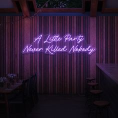 a purple neon sign that says a little party never killed nobody on the wall behind it