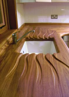 a wooden counter top with a sink and faucet in the center, next to a mirror