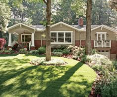 a house in the woods with lots of trees and flowers on the front lawns