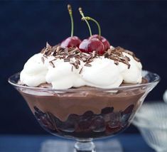 a dessert with whipped cream, cherries and chocolate shavings on top in a glass dish