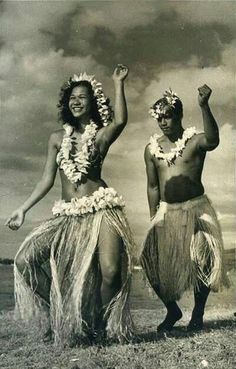 two women in hula skirts dancing on the beach