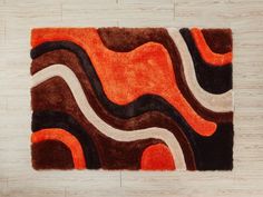 an orange and brown area rug with wavy lines on the floor in front of a white wall