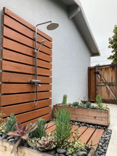 an outdoor shower with wooden slats and succulents