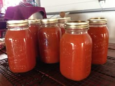 four jars filled with red liquid sitting on top of a metal rack