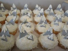 cupcakes with white frosting and silver decorations in a box on a table