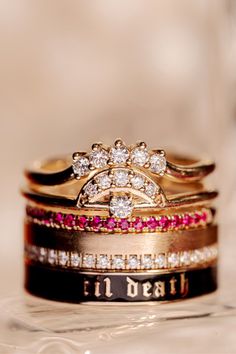 a stack of wedding rings with pink and white stones on them sitting on top of each other